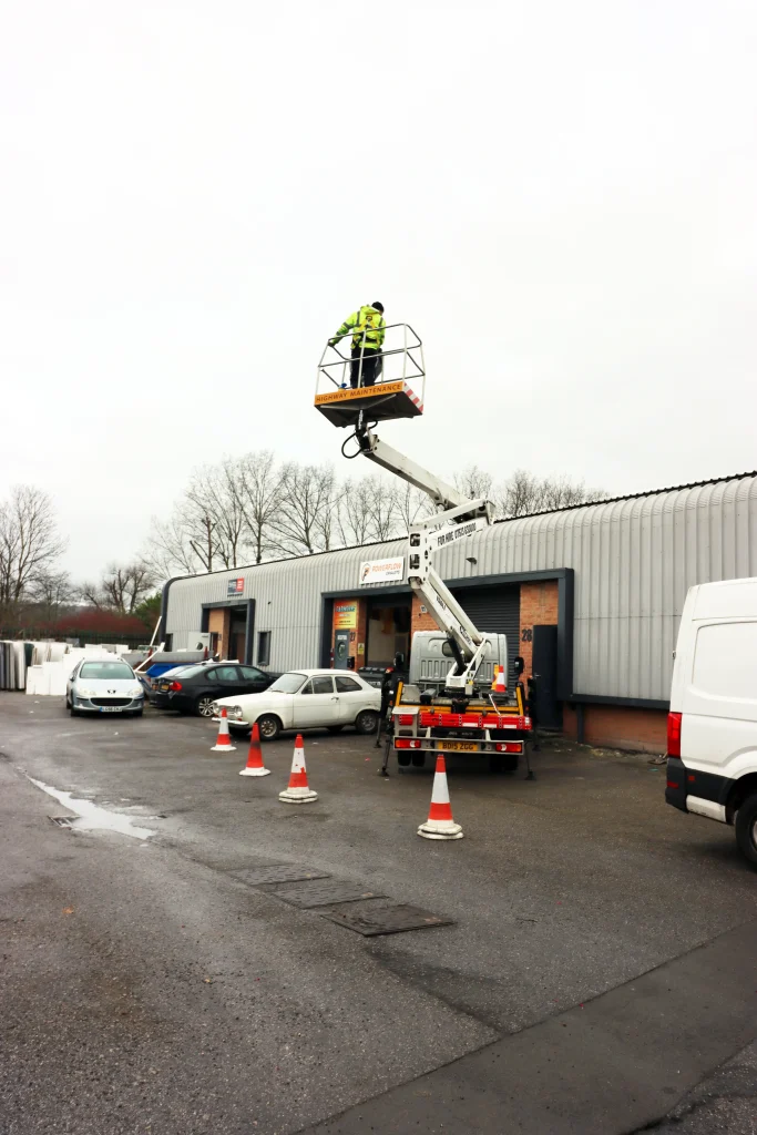 Operator using a cherry picker for roof repair near a skylight